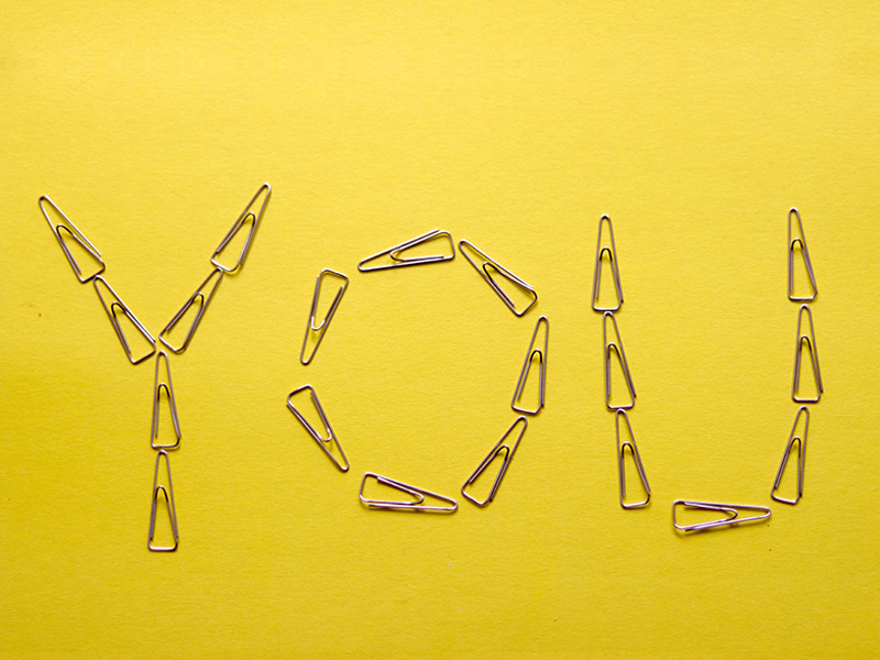 The word "You" spelled out on a yellow background with paper clips