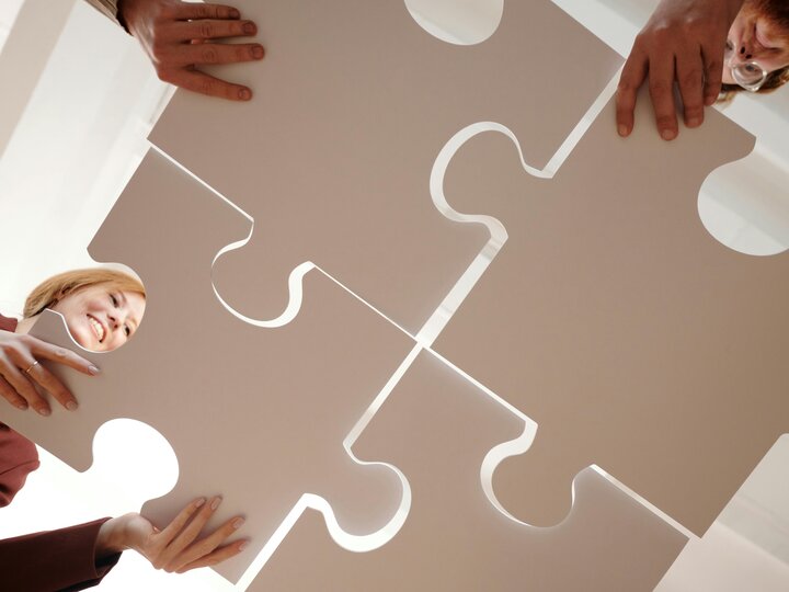 People Holding Gray Puzzle Pieces