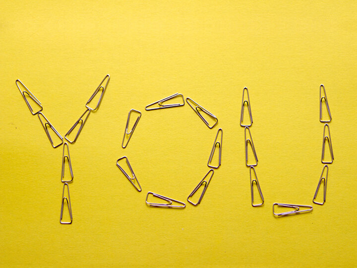 The word "You" spelled out on a yellow background with paper clips