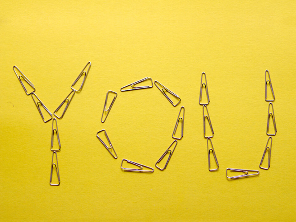 The word "You" spelled out on a yellow background with paper clips